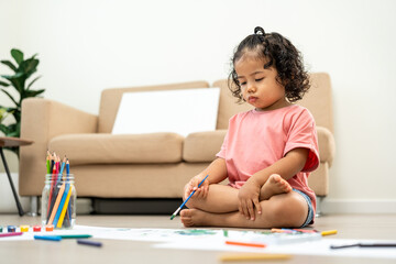 Naklejka premium Happy moment little cute girl creating and water color painting activity with paint brushes on frame canvas at living room. Kids activity. Child physical, Emotional, Cognitive development concept.