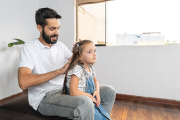 Father is brushing the hair of his daughter at home