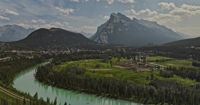 Banff AB Canada Aerial v47 picturesque landscape of glacier-fed Bow river, stables in meadows, quaint foothill town, forested valley and Rundle mountain ranges - Shot with Mavic 3 Pro Cine - July 2023