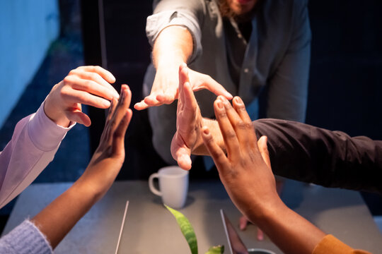 This image captures the hands of a professional team mid-celebration, giving a high five in a show of unity and success. The photo includes diverse team members, represented by a variety of skin