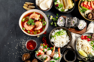 Traditional Asian food table. Spring roll, rice, shrimp, sushi, vegetables, meat on dark background