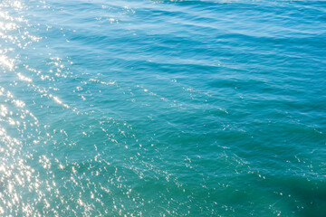 Blue sea water surface with sun reflection. Natural background and texture.