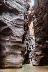 The not  very deep Mujib River flows between high cliffs along Mujib River Canyon hiking trail in Wadi Al Mujib in Jordan