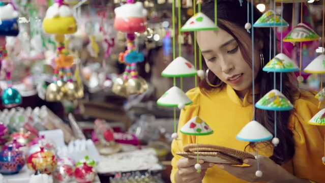 Young woman in yellow Ao Dai admiring crafts at Hoi An market, vibrant colors, close-up