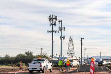 Two construction workers stand at the median of a road where an improvement project is underway....