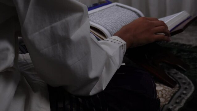 man reading holy quran on mini wooden table with curtain background