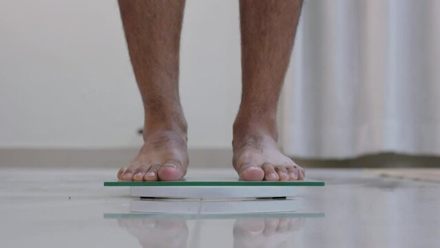 Man Analyzing Weight while Standing on Weight Scale