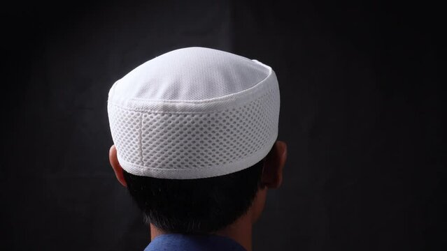muslim man wear a white skull cap or hat with isolated black background