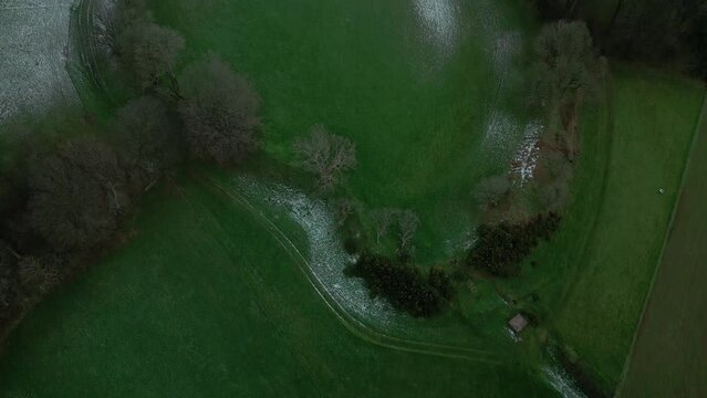 Cadbury Castle iron age hilltop fort aerial drone top down tilt footage during a sprinkling of snow