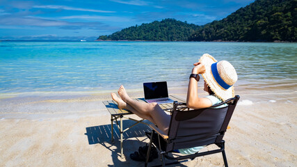 Nomad digital with laptop and running remotely with bright scenic view near poolside on the beach...
