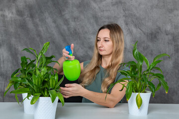 Blond-haired girl nurturing green plants with a sprinkler at a wooden table