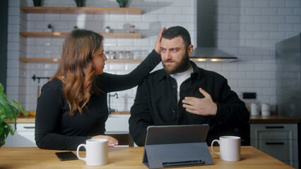 Young couple sit in kitchen while man suffering chest pain, holding massaging his chest, his girlfriend get worry and check him. Health problems concept	
