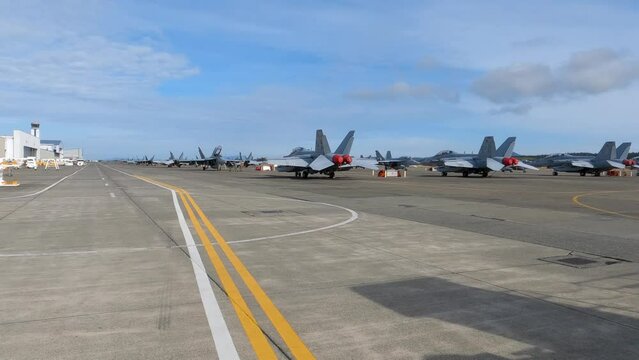 Lines of fighter jets sitting on the Naval runway, ready to deploy.