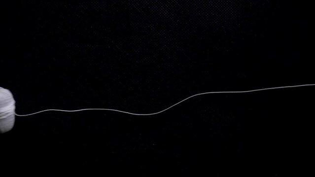 white thread spool ball roll on black background static high angle
