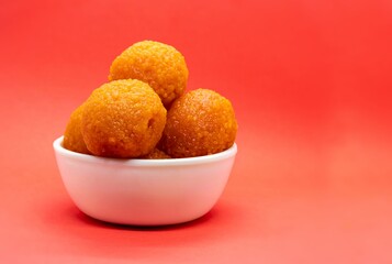 Motichoor Laddu or Motichur Ladoo in a White Bowl Isolated on Red Background with Copy Space