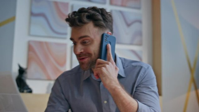 Closeup excited winner calling mobile phone sitting office. Happy businessman
