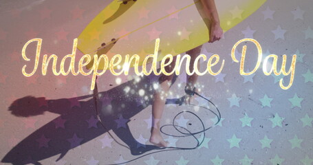Person carries a yellow surfboard under the Independence Day text