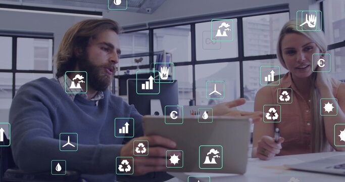 Image of ecology icons over caucasian business people using tablet