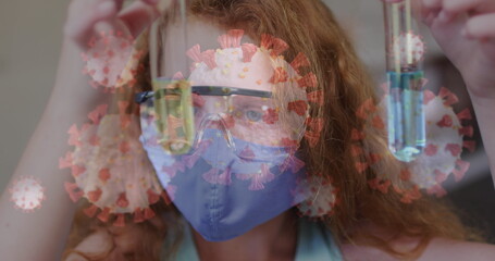 Image of covid 19 cells and schoolgirl in science class wearing face mask