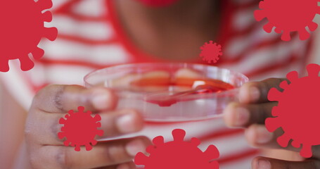 Child examining a petri dish with a red substance, surrounded by virus graphics