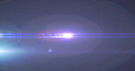 Image of spotlight with lens flare and light beams moving over dark background