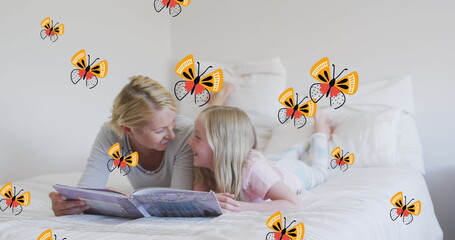 Image of butterflies over happy caucasian mother and daughter reading book in bed