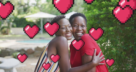 Image of hearts over smiling african american mother and daughter in garden