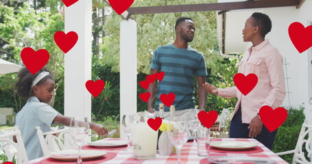 Image of hearts over happy african american family preparing meal in garden