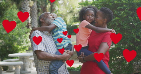 Image of hearts over happy african american multi generation family hugging in garden