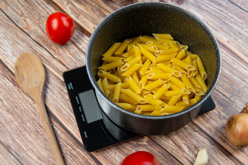 Preparing healthy and nutritious pasta. Weighing pasta on a kitchen scale, counting calories and checking macronutrients. Healthy Mediterranean diet - obrazy, fototapety, plakaty