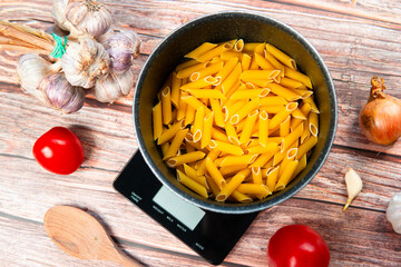 Preparing healthy and nutritious pasta. Weighing pasta on a kitchen scale, counting calories and...