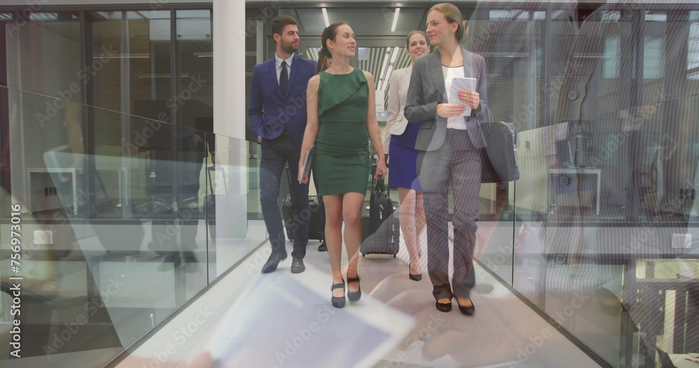 Wall mural Image of smiling man working on laptop over happy colleagues with luggage walking in corridor