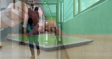 Image of hands of man using tablet, over businessman walking in workplace corridor