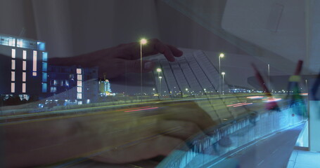 Image of hands working on laptop over sped up traffic in city at night