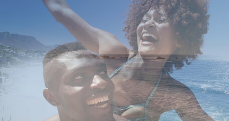 Image of happy african american couple having fun at beach over sea