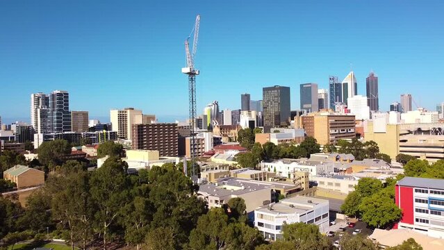 Slow aerial reverse shot of tower crane on construction site with Perth City buildings in the background