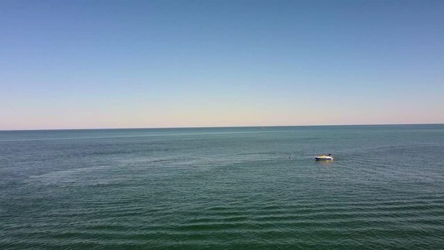 Aerial flyover calm ocean with small boat enjoying watersports
