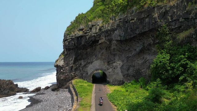 Sao Tome Santa Caterina tunnel and face rock, moped driving through - Aerial view