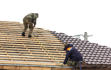 Workers install tiles on the roof of a house in winter - 756980248