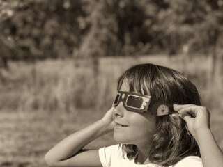 A young girl looking at the sun during a solar eclipse on a country park, family outdoor activity - 756981286