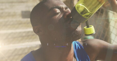 Image of glowing lights over an exercising african american man drinking water