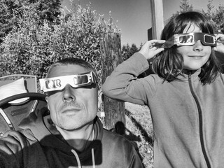 Father and daughter, family viewing solar eclipse with special glasses in a park - 756982899