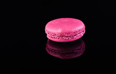 Assorted colorful macarons folded and arranged on a black surface with reflection