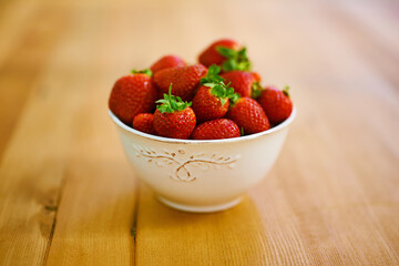 Wellness, health and strawberry bowl in kitchen of home, on wooden counter top for diet or nutrition. Food, fruit and lose weight with berries on surface in apartment for detox, minerals or vitamins