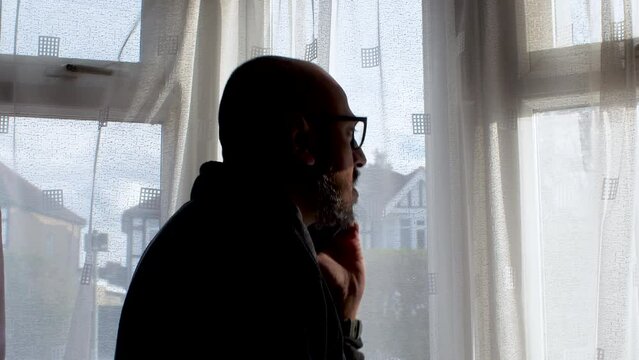 Silhouette Of Bald Male Talking On Phone Beside Window Curtains Moving Side To Side Evoking Nosey Neighbour, Observational Concept. Static Shot