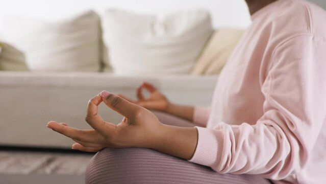 Woman sitting at home in living room practicing yoga