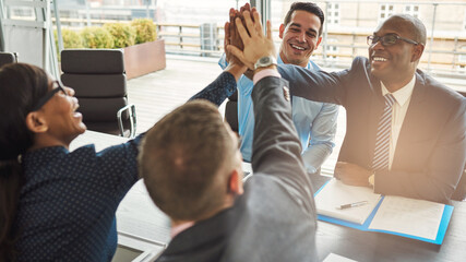 Group of happy successful business people smiling and high fiving each other during a meeting in an office. Businessmen and women showing teamwork, collaboration in a diverse workplace. - 756994405