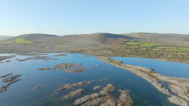 Panoramic aerial establishes blue sky reflecting in flood waters on Burren Ireland with stunning rock formations