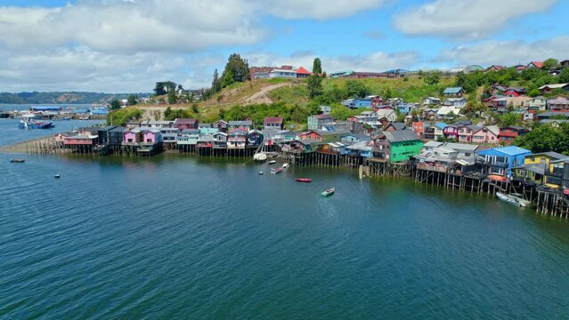 Drone shot of boats at the Palafitos stilt houses, sunny day in Castro city, Chile