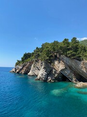 Naklejka premium Turquoise Cove: Rugged Cliffs, Lush Pines